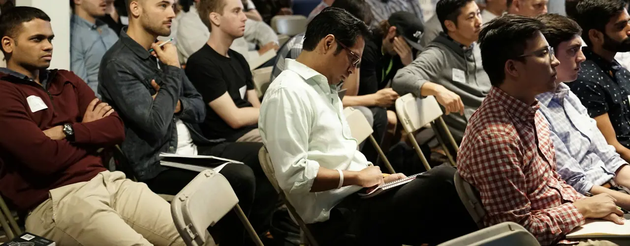 An audience listening closely to a talk, some taking notes