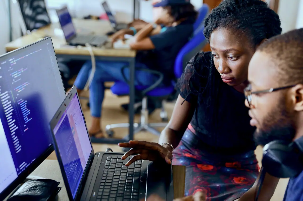 Two people working through code together on a laptop