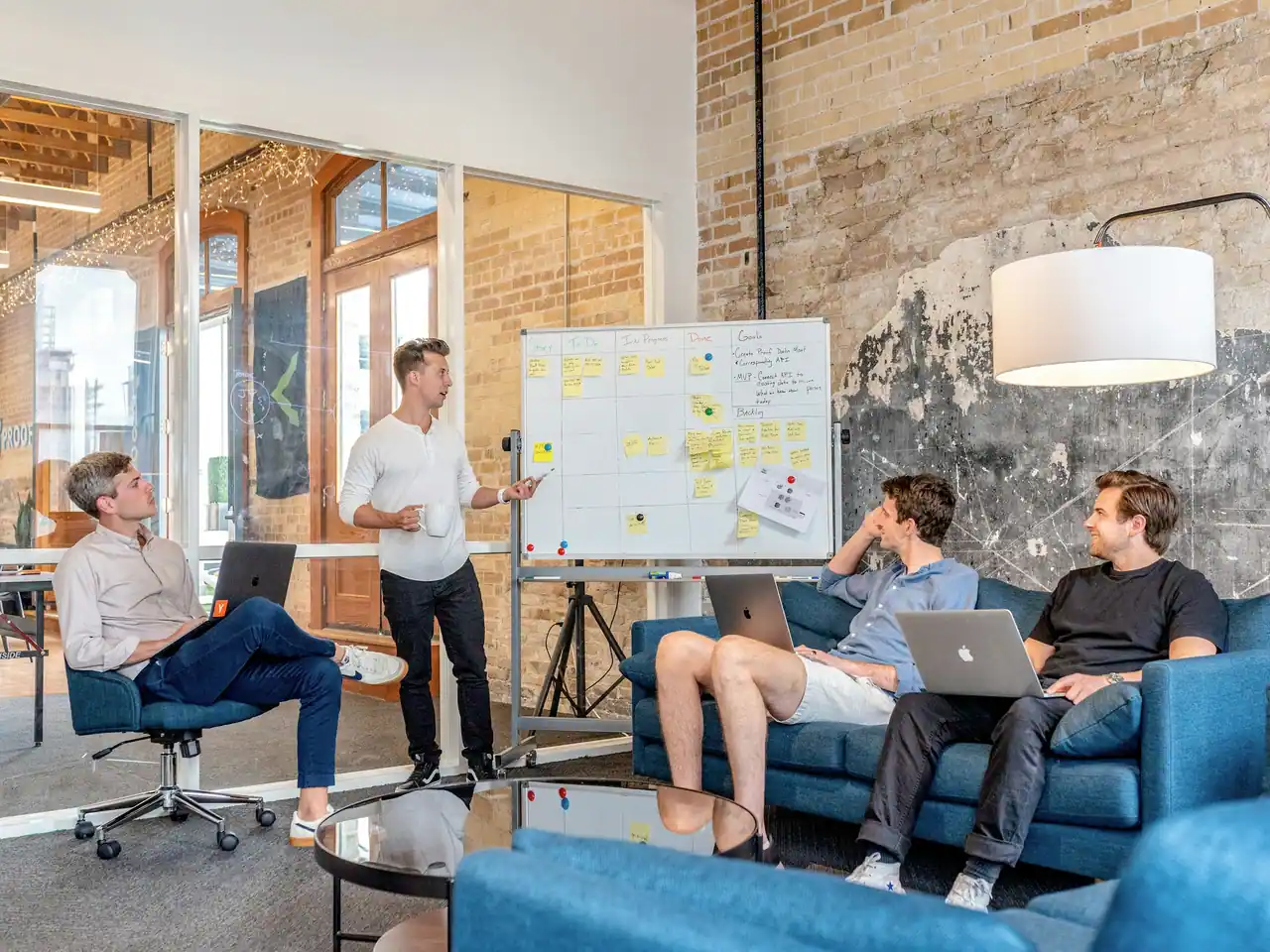 A small team in a loft office planning at a whiteboard covered in notes